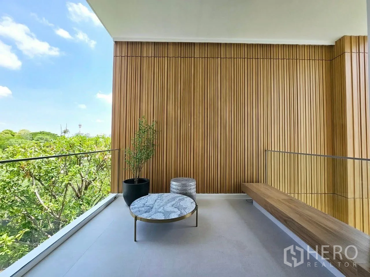 Detached House for rent in Saphan Sung, Bangkok - Covered balcony with wood cladding, marble coffee table, and bench seating over greenery.