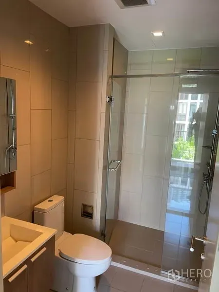 Condominium for sale in Watthana, Bangkok - Tiled bathroom with a glass-enclosed shower, vanity, and toilet.