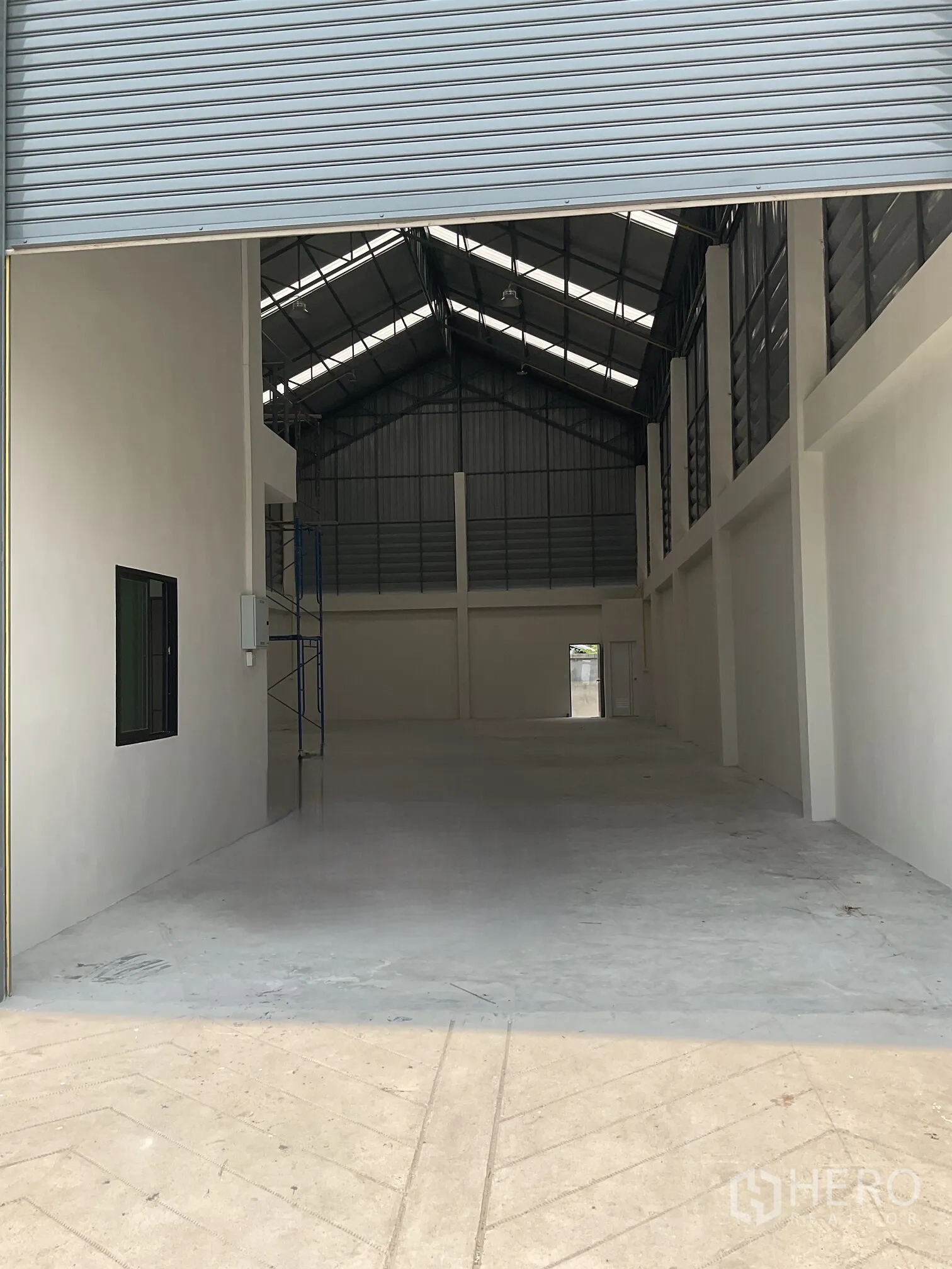 Warehouse for rent in Lat Lum Kaeo, Pathum Thani - Open warehouse interior with high gable roof, concrete floor, and a mezzanine office by the entrance.