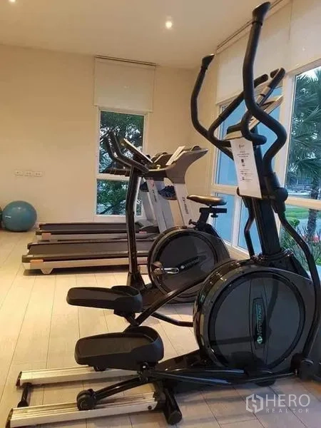 Detached House for rent or sale in Saphan Sung, Bangkok - Fitness room with treadmills and elliptical machines overlooking trees.