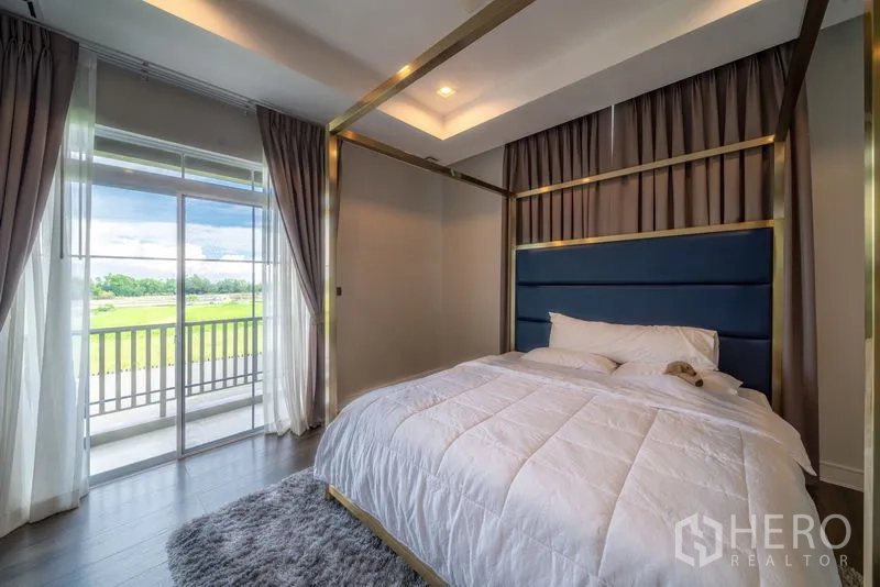 Detached House for rent in Bang Khen, Bangkok - Master bedroom with canopy bed, floor-to-ceiling curtains and balcony overlooking greenery.