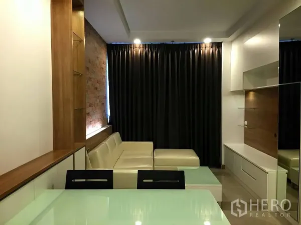 公寓 出售在Huai Khwang, Bangkok - 现代客厅，米色转角沙发、砖纹特色墙、电视柜与遮光窗帘，位于Huai Khwang公寓内。