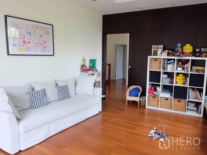 บ้าน ให้เช่าในWatthana, Bangkok - ห้องนั่งเล่นชั้นบนพร้อมโซฟาสีขาวและชั้นวางแบบช่องสำหรับหนังสือและของเล่น