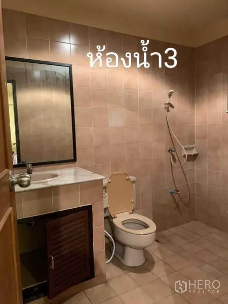 Townhouse for rent in Phra Khanong, Bangkok - Tiled bathroom with vanity, mirror, toilet, and handheld shower.