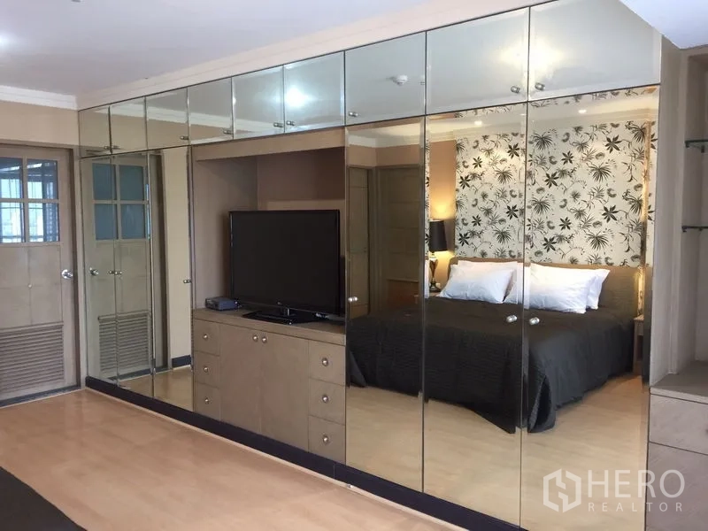 Condominium for rent in Watthana, Bangkok - Bedroom with full-height mirrored wardrobes and TV cabinet reflecting the bed area.
