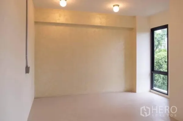 Home Office for rent or sale in Lak Si, Bangkok - Private room with light-colored walls and a corner window facing trees.