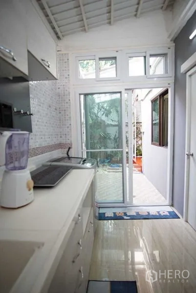 Townhouse for rent in Suan Luang, Bangkok - Kitchen view toward sliding glass doors opening to a small patio with plants.