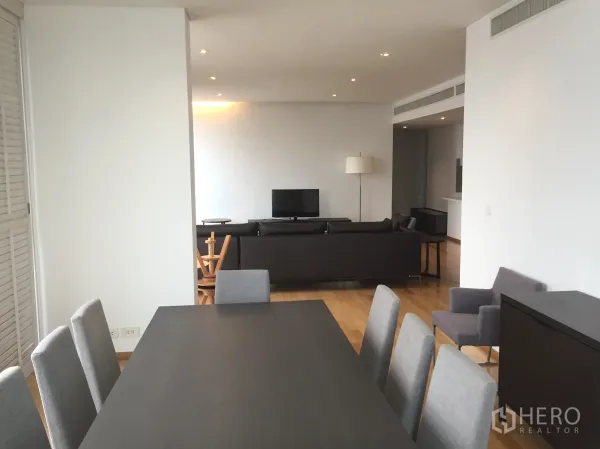 公寓 出租或出售在Watthana, Bangkok - 开放式客餐厅，木地板，灰色餐椅，沙发面向电视。