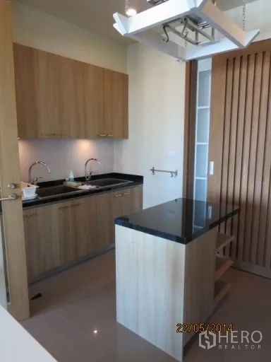 Condominium for rent in Bang Rak, Bangkok - Modern kitchen with black granite island, twin sinks and wood cabinetry.