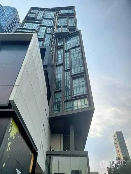 公寓 出租在Watthana, Bangkok - 现代高层公寓外观，街道仰视，几何感玻璃立面。