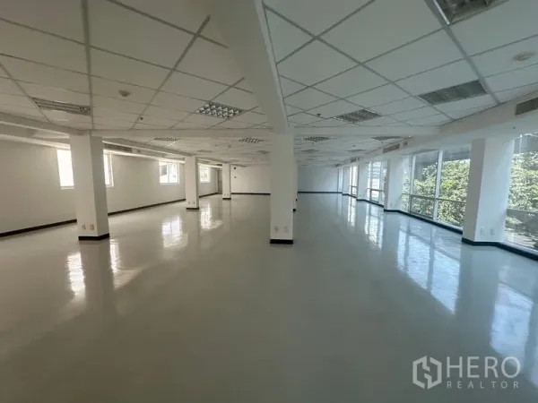 办公空间 出租在Phaya Thai, Bangkok - 大面积柱间空间，亮面地坪、栅格天花灯具与整面窗户，俯瞰城市绿景。