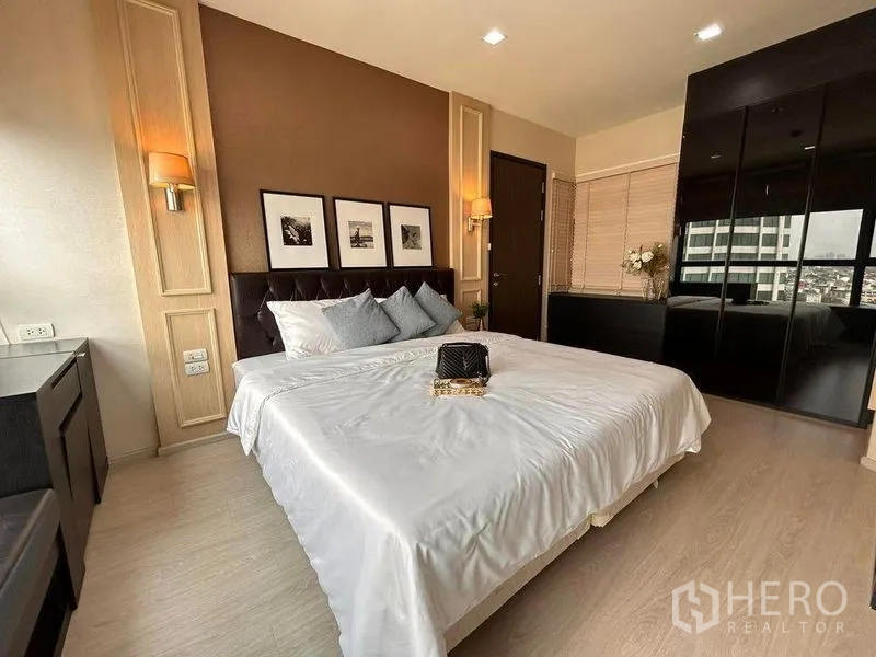 Condominium for rent or sale in Khlong Toei, Bangkok - Elegant bedroom featuring a king bed, wall sconces and glossy built-in wardrobe.