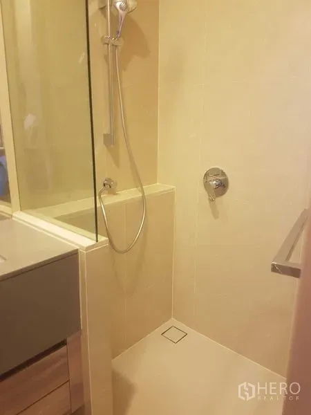 公寓 出租在Watthana, Bangkok - 米色瓷砖浴室，玻璃隔断淋浴间与手持花洒。