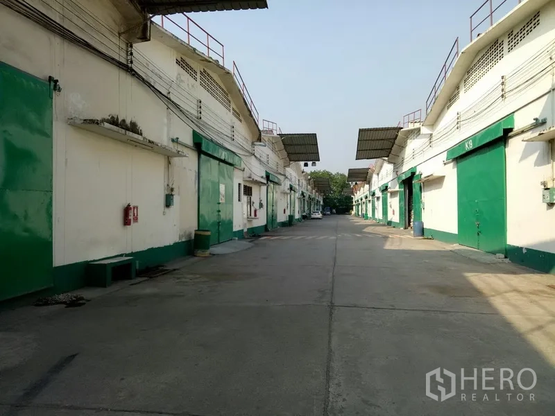 Warehouse for rent in Khlong Toei, Bangkok - Row of warehouse blocks with green loading bay doors along a wide internal driveway for trucks.