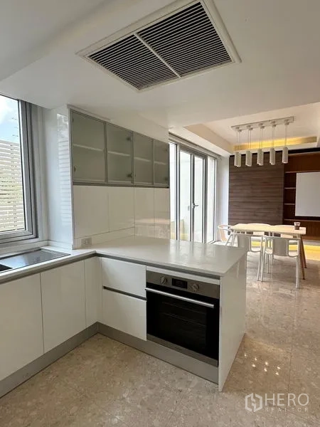 Townhouse for sale in Yan Nawa, Bangkok - Kitchen with built-in oven, breakfast counter and adjacent dining area under linear pendant lights.