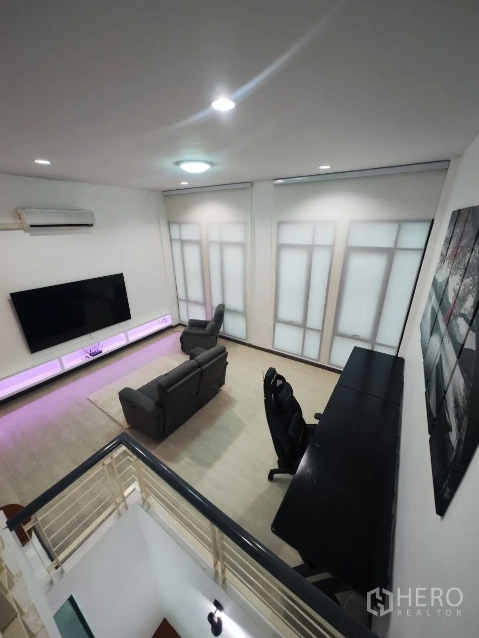 Home Office for rent in Bang Na, Bangkok - Spacious living area with sofas, large TV wall, desk and recessed lighting.