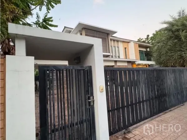 Detached House for sale in Saphan Sung, Bangkok - Secure pedestrian gate and driveway entrance with vertical slat fence of a contemporary home.