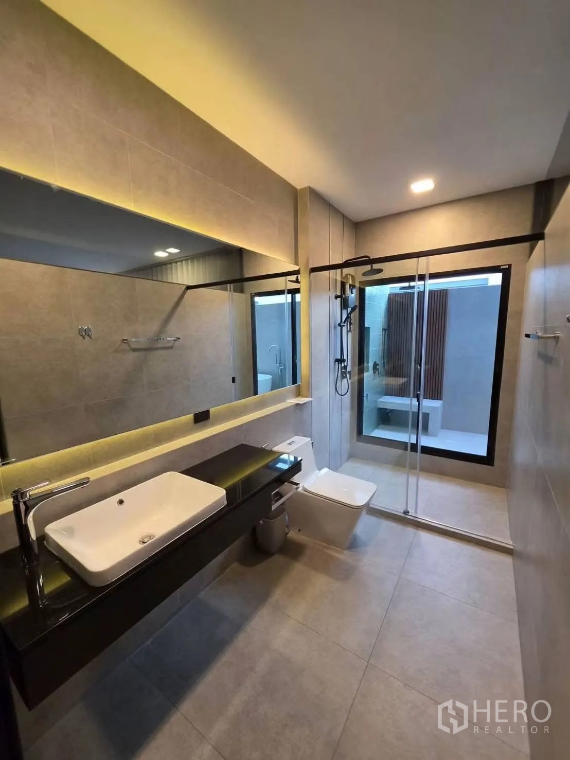 Townhouse for rent in Bang Phli, Samut Prakan - Modern bathroom with long vanity, LED mirror, toilet, and glass shower enclosure.