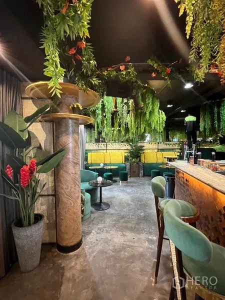 พื้นที่ขายปลีก ให้เช่าในWatthana, Bangkok - โซนเลานจ์โซฟาสีเขียว เสาตกแต่ง และต้นไม้ข้างบาร์