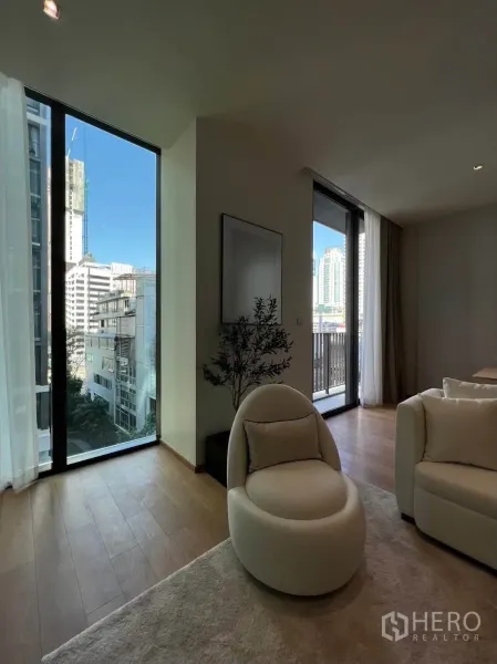 Condominium for rent in Pathum Wan, Bangkok - Seating nook beside tall windows and a balcony door with city views.