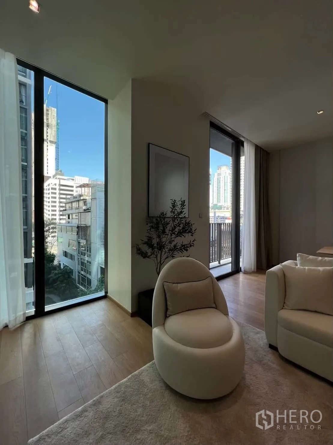 Condominium for rent in Pathum Wan, Bangkok - Seating nook beside tall windows and a balcony door with city views.