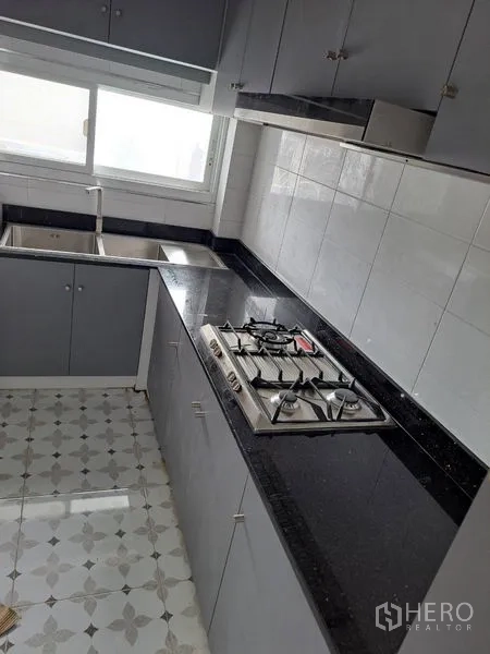 独立式住宅 出租在Prawet, Bangkok - 整体厨房配黑色花岗岩台面、燃气灶与窗边双槽水槽。
