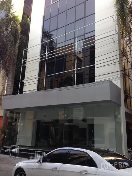 Office Space for rent in Bang Kapi, Bangkok - Modern glass-façade office building with a clear ground-floor entrance and palm trees along the frontage.