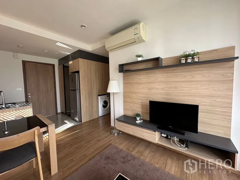Condominium for rent in Watthana, Bangkok - Living area media wall with TV, shelves, air conditioner, and wood paneling.