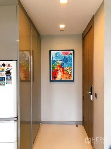 Condominium for rent in Bang Rak, Bangkok - Entry hallway with built-in cabinets and colorful framed artwork.