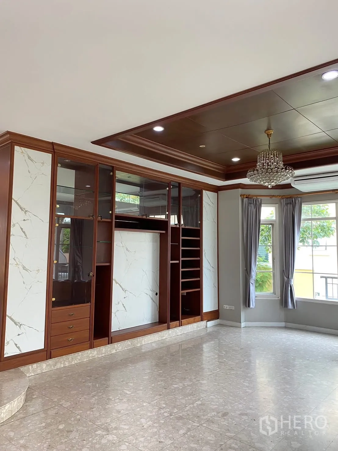 Detached House for rent in Phra Khanong, Bangkok - Living area with wall-to-wall display cabinetry, chandelier, recessed ceiling, and bay window.