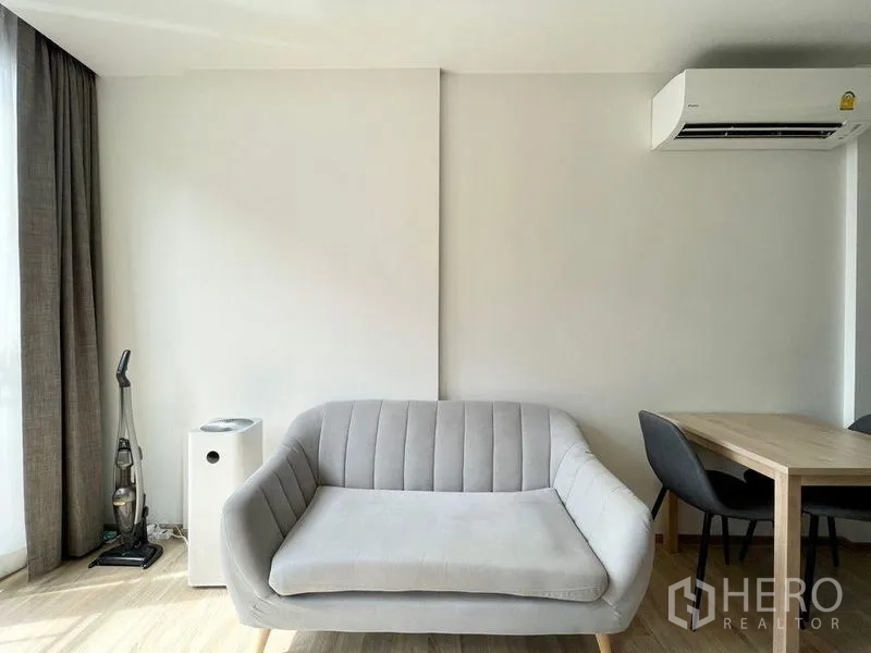 公寓 出租或出售在Watthana, Bangkok - 客厅一角，灰色沙发、餐桌与大窗，采光良好。