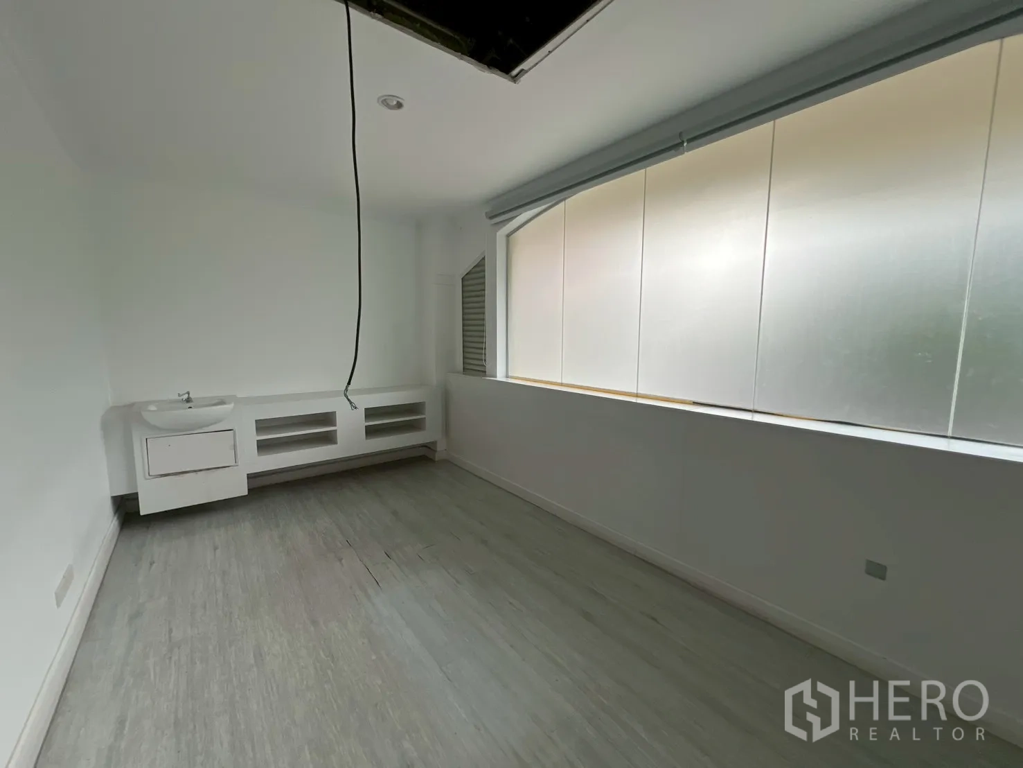 Office Space for rent in Watthana, Bangkok - Bright room with long frosted windows, light floor and wall-mounted sink with cabinets.