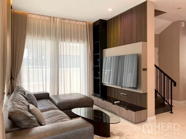 บ้าน ให้เช่าในBang Phli, Samut Prakan - ห้องนั่งเล่นอบอุ่น โซฟาหนังตัวแอล ชุดทีวีบิวท์อิน และบันไดบ้าน