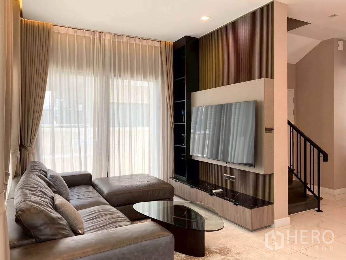 บ้าน ให้เช่าในBang Phli, Samut Prakan - ห้องนั่งเล่นอบอุ่น โซฟาหนังตัวแอล ชุดทีวีบิวท์อิน และบันไดบ้าน