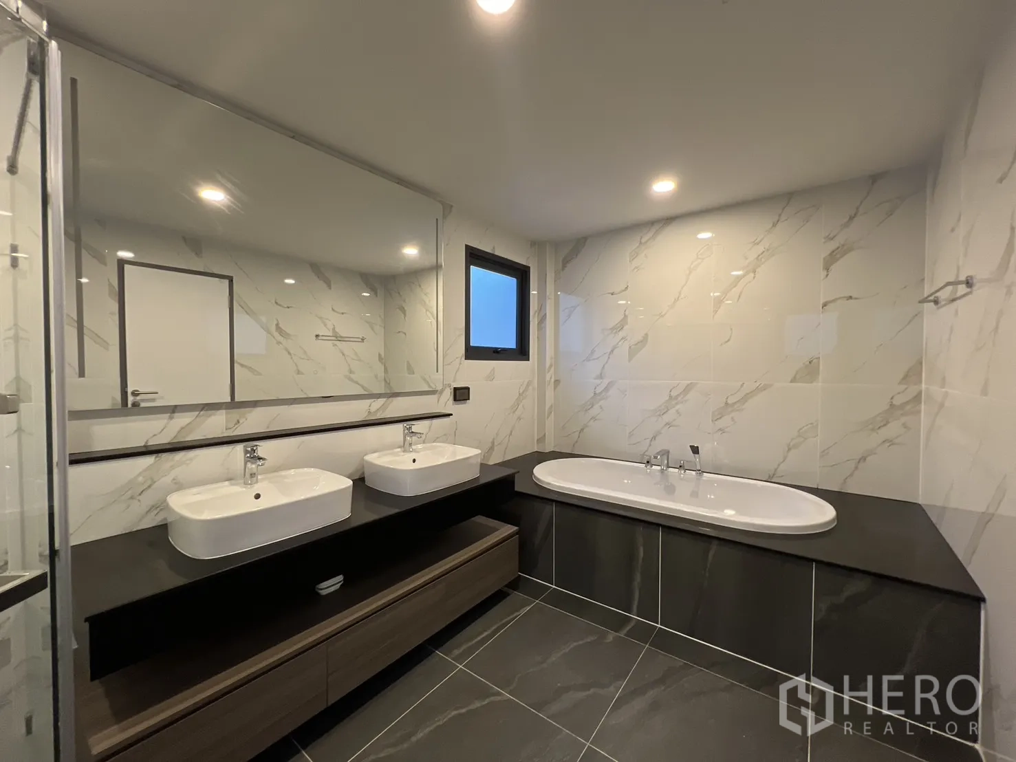 Detached House for rent in Bang Phli, Samut Prakan - Master bathroom with double vanity, bathtub and marble-look wall tiles.