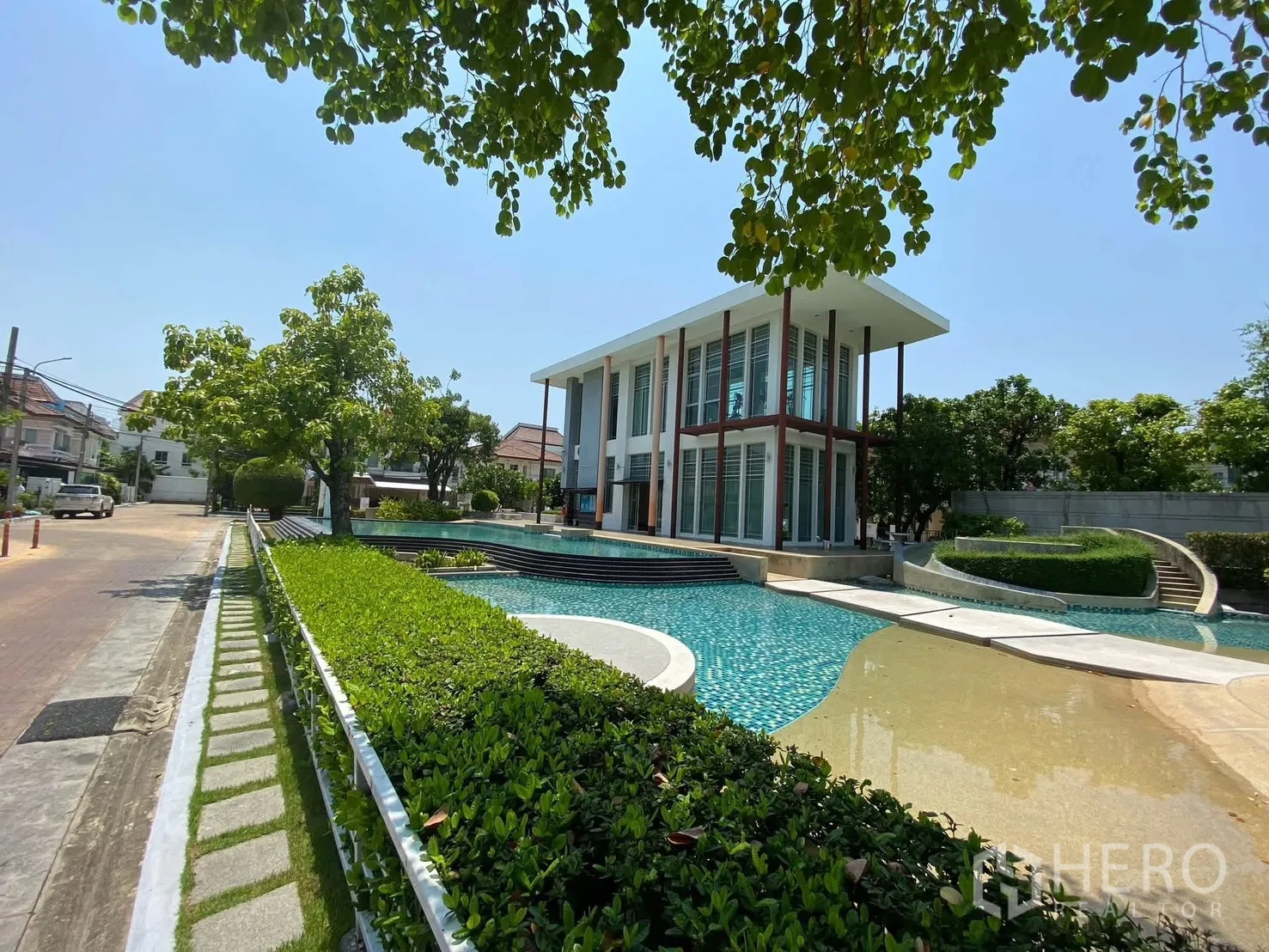 独栋房屋 for rent in Mueang Samut Prakan, Samut Prakan - 现代风格会所临泳池而建，周围景观葱郁。
