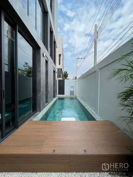 带办公室的家 出售在Prawet, Bangkok - 建筑旁的私家狭长泳道，设木质平台与高隐私围墙。