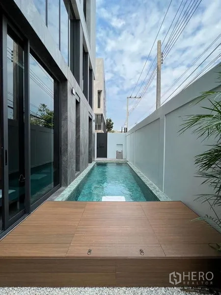 带办公室的家 出售在Prawet, Bangkok - 建筑旁的私家狭长泳道，设木质平台与高隐私围墙。