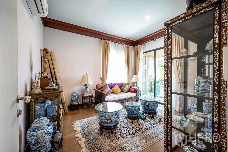 独立式住宅 出售在Prawet, Bangkok - 温馨会客室，玻璃展示柜与泰式瓷器，靠近推拉门。