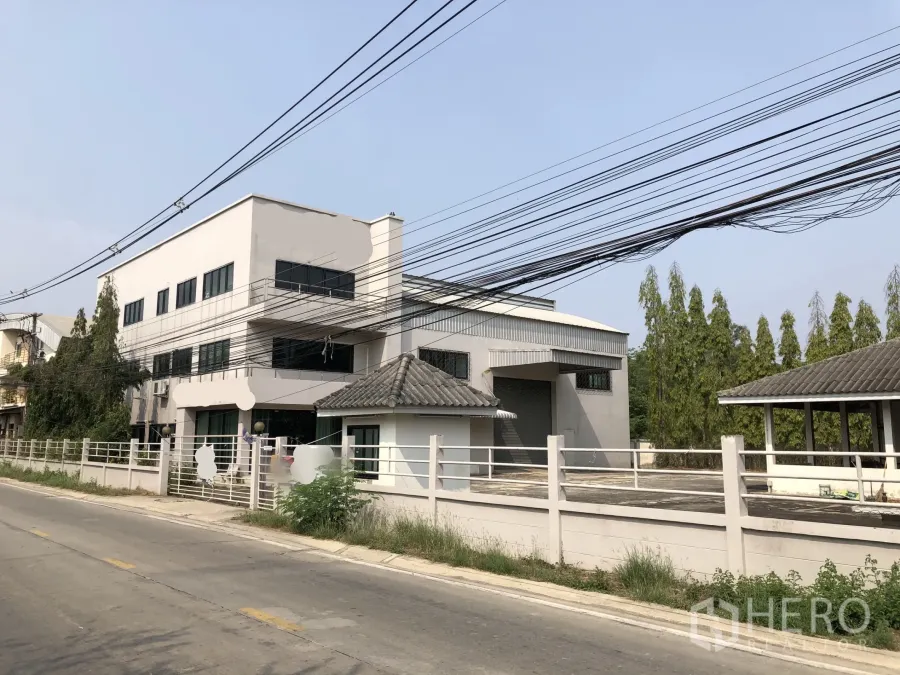 工厂 出售在Lam Luk Ka, Pathum Thani - 工厂正面外观，带办公楼、装卸区与围墙，临安静道路。