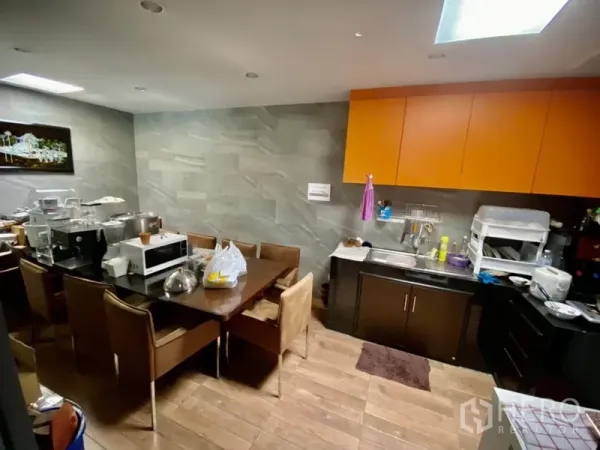 Home Office for rent or sale in Yan Nawa, Bangkok - Pantry and dining area with stone tile walls, orange overhead cabinets, and a long table.