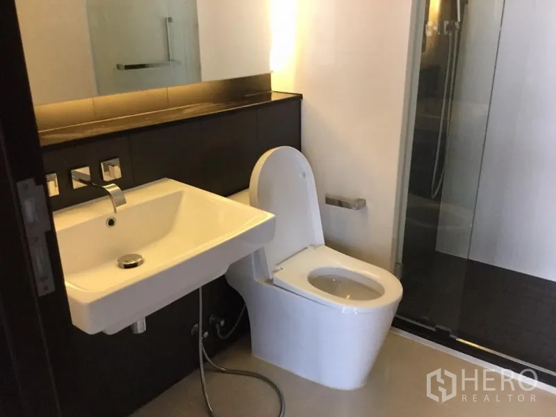 คอนโด ให้เช่าในHuai Khwang, Bangkok - ห้องน้ำสมัยใหม่พร้อมอ่างล้างหน้าแบบติดผนัง โถสุขภัณฑ์ และตู้ชาวเวอร์กระจก
