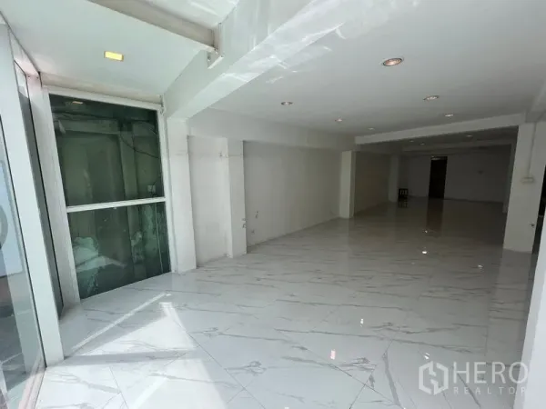 零售空间 出租在Khlong Toei, Bangkok - 长形展厅，天花嵌灯、白色墙面，入口旁设玻璃电梯。