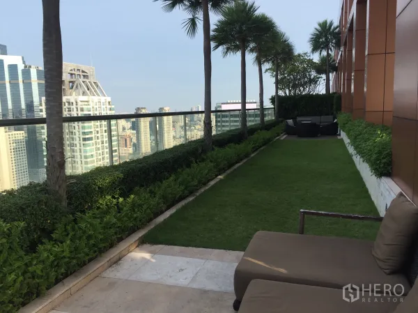 Condominium for rent or sale in Bang Rak, Bangkok - Sky garden terrace with lawn, palm trees and lounge seating above the city.