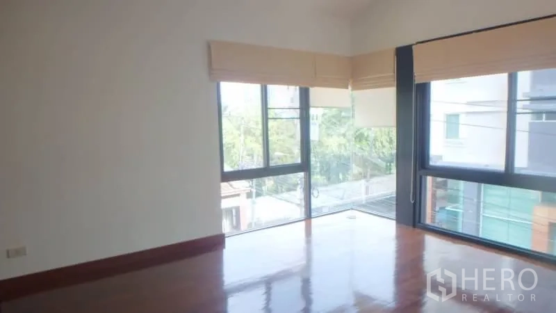 Detached House for rent in Watthana, Bangkok - Bright corner bedroom with large windows and polished wooden flooring.