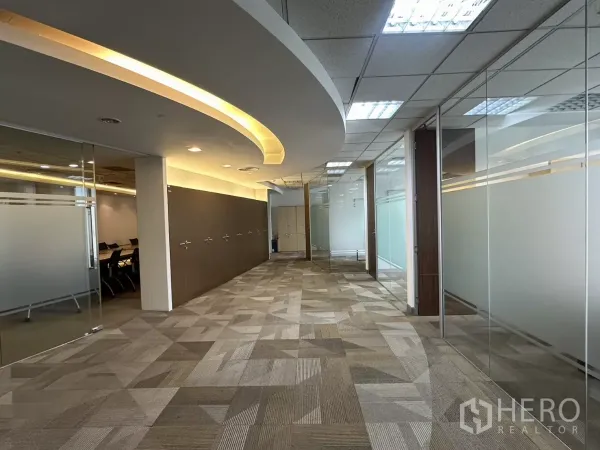 Office Space for rent in Watthana, Bangkok - Corridor with glass walls and recessed lighting leading to meeting rooms.