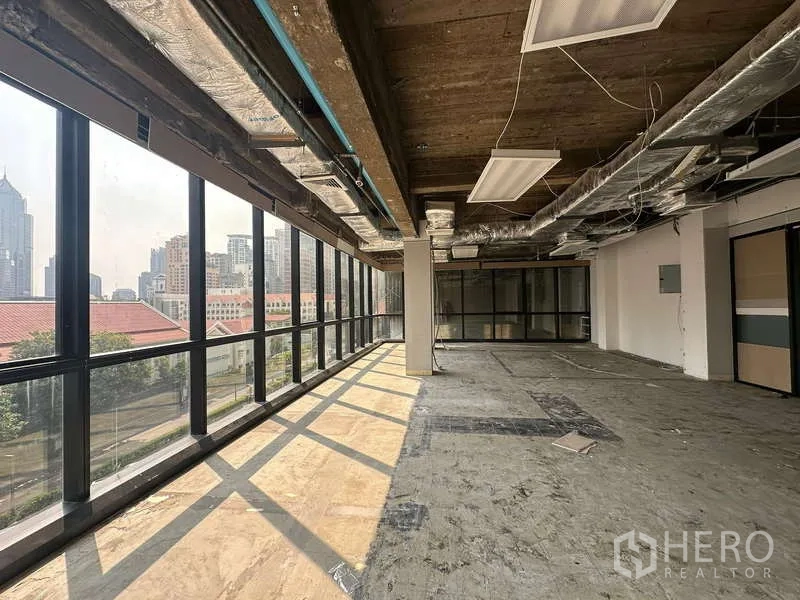 Office Space for rent - Corner open-plan office with floor-to-ceiling windows, exposed ceiling and ducted AC overlooking the Bangkok skyline.