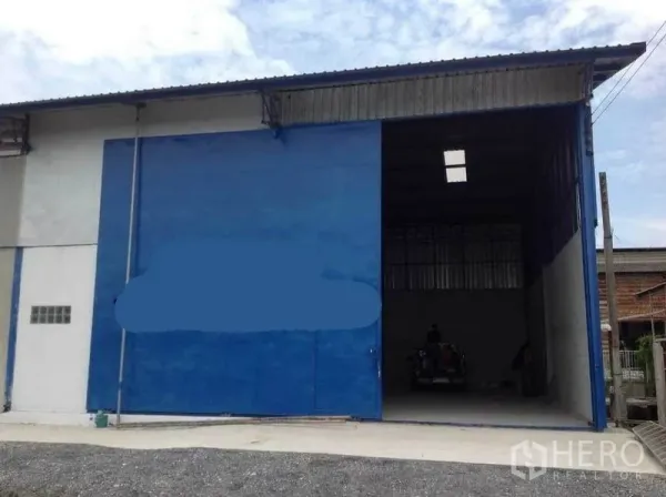 Factory for rent in Mueang Nakhon Pathom, Nakhon Pathom - Front facade of the factory with an extra‑tall blue sliding door open for truck loading.
