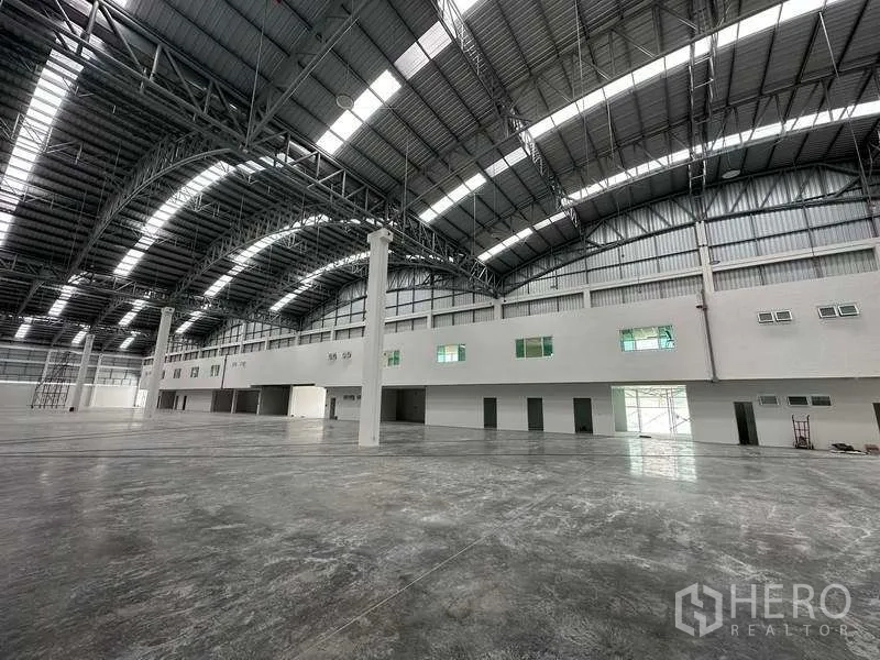 Factory for rent in Khlong Luang, Pathum Thani - Long-span warehouse showing mezzanine-style office line and multiple service doors.