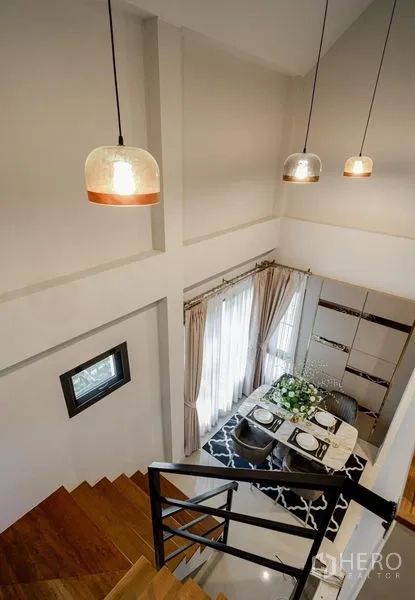 Detached House for sale in Lam Luk Ka, Pathum Thani - Staircase view to a double-height dining area with pendant lights.